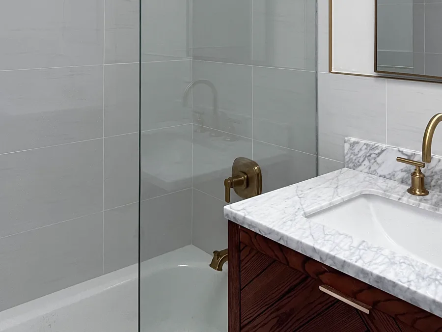 Bathroom with a glass shower screen, marble vanity top and brass fixtures