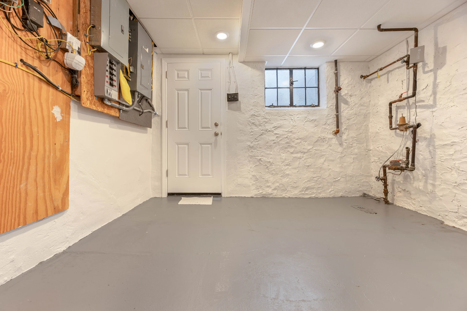 Finished basement with a new white door and a sealed concrete floor