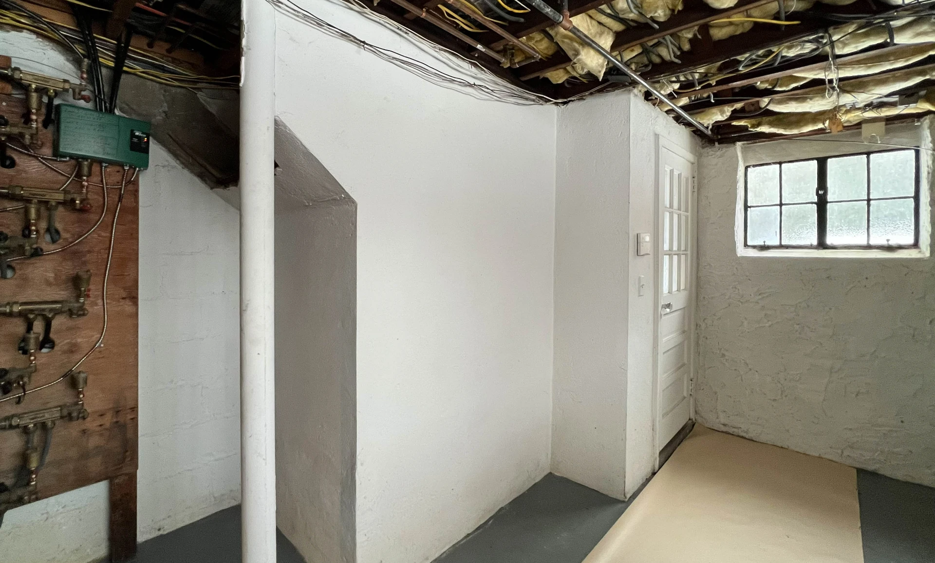 Before: unfinished basement with exposed joists and open services