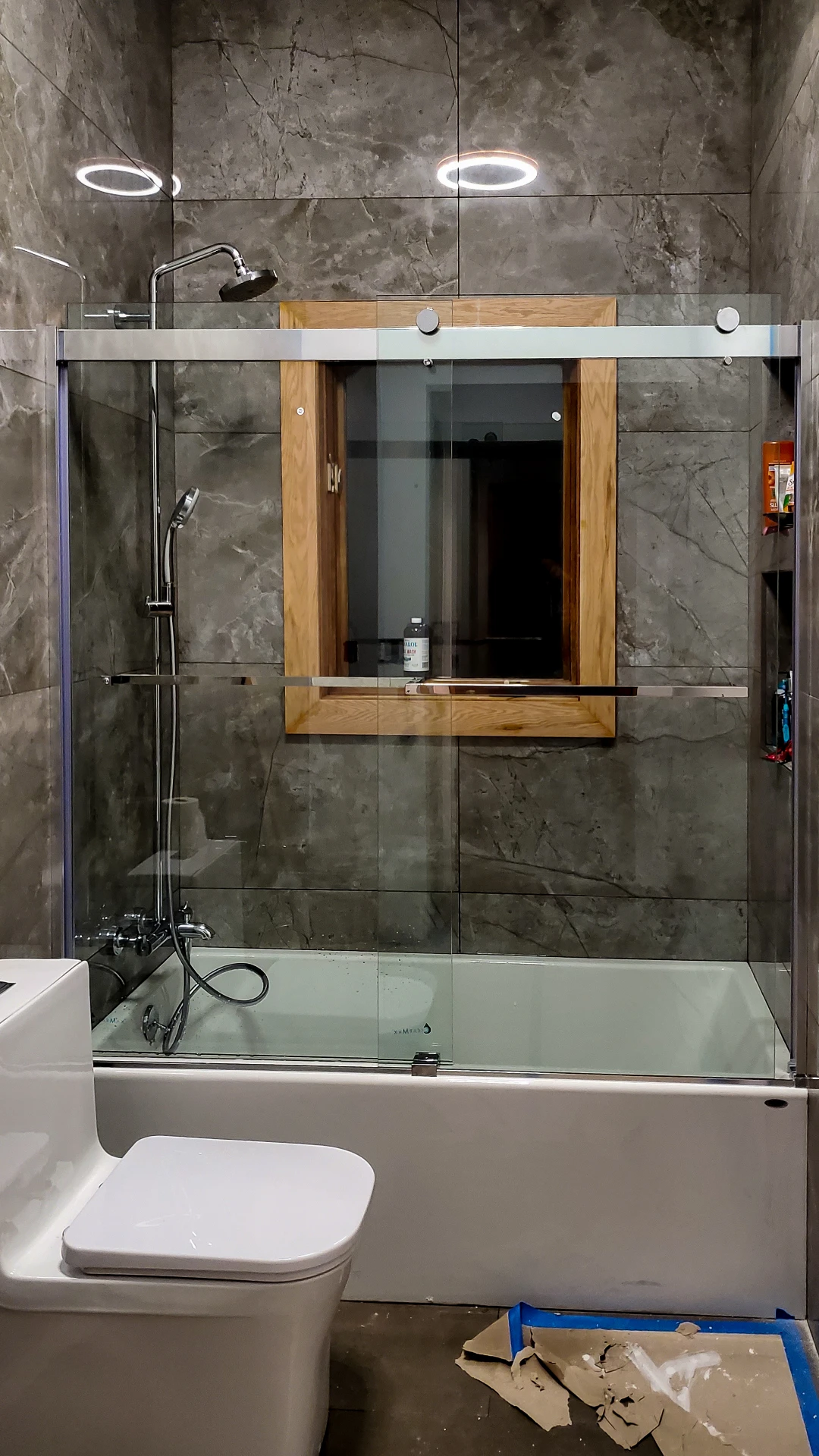 Finished bathroom in grey marble tile with a glass shower enclosure