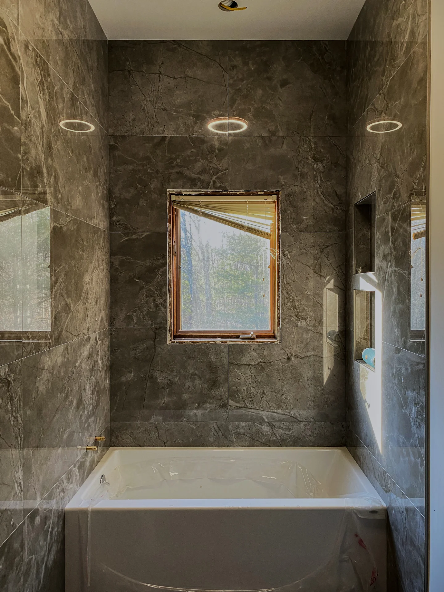 Finished grey marble bathroom with ring lighting and a full height mirror