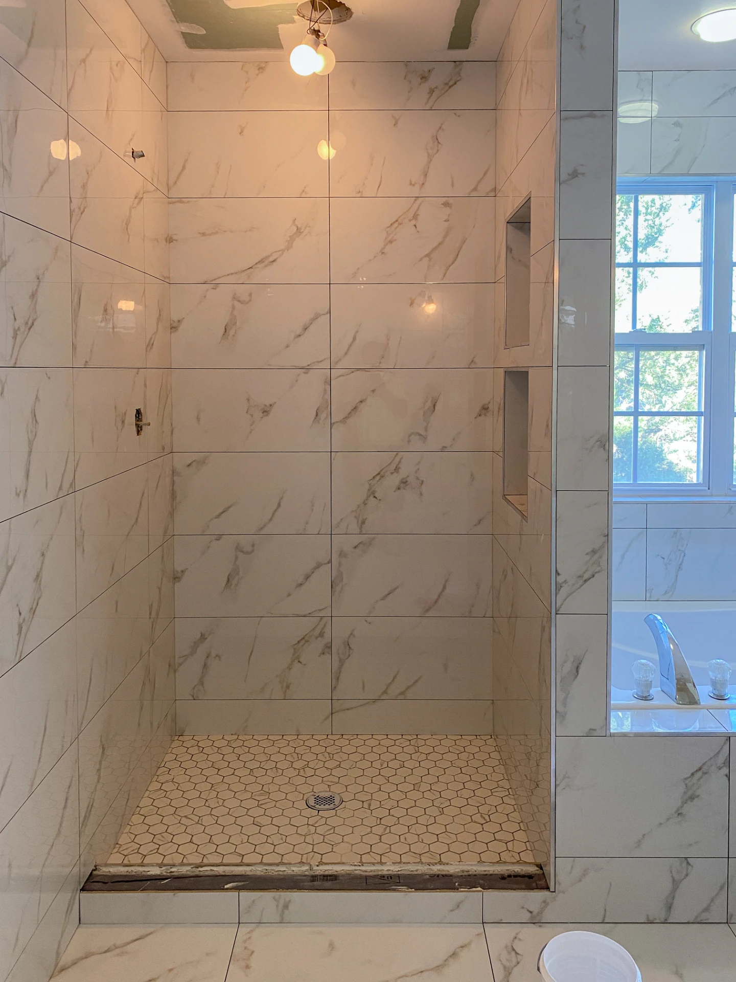 Finished white marble tiled shower with a window