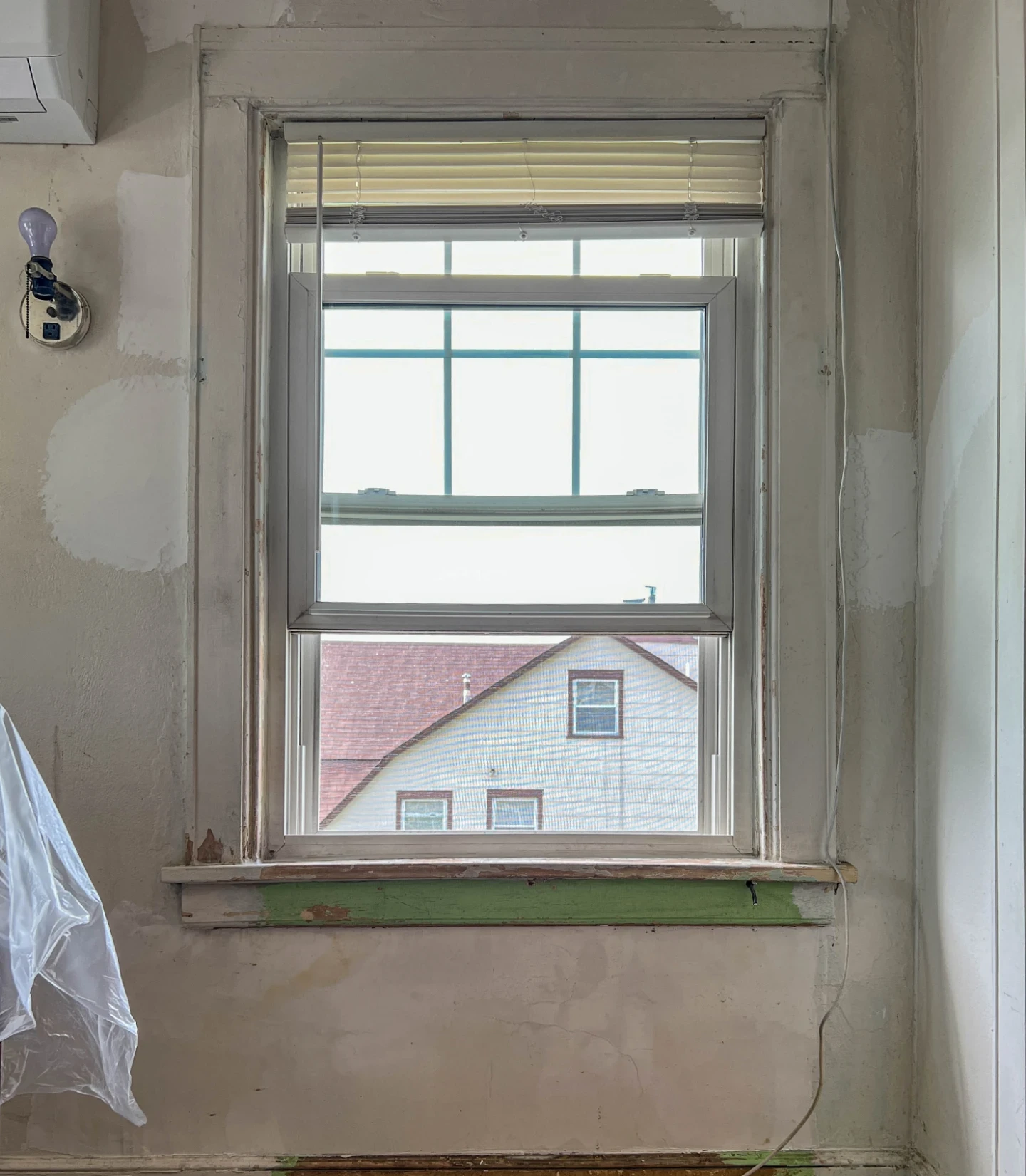 Before: window wall with patched plaster and bare trim