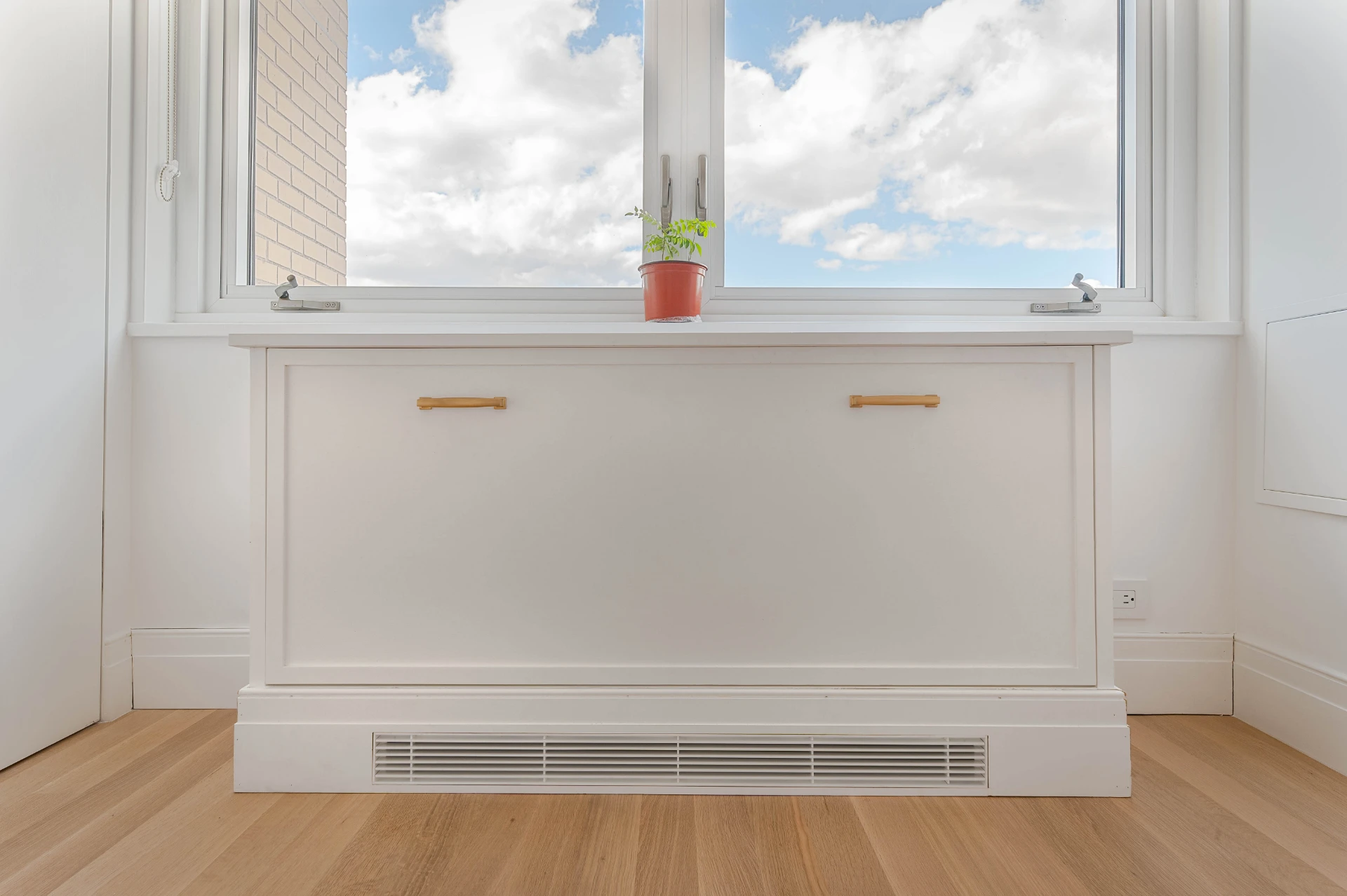 Built in bench and radiator cover in painted wood, under a window