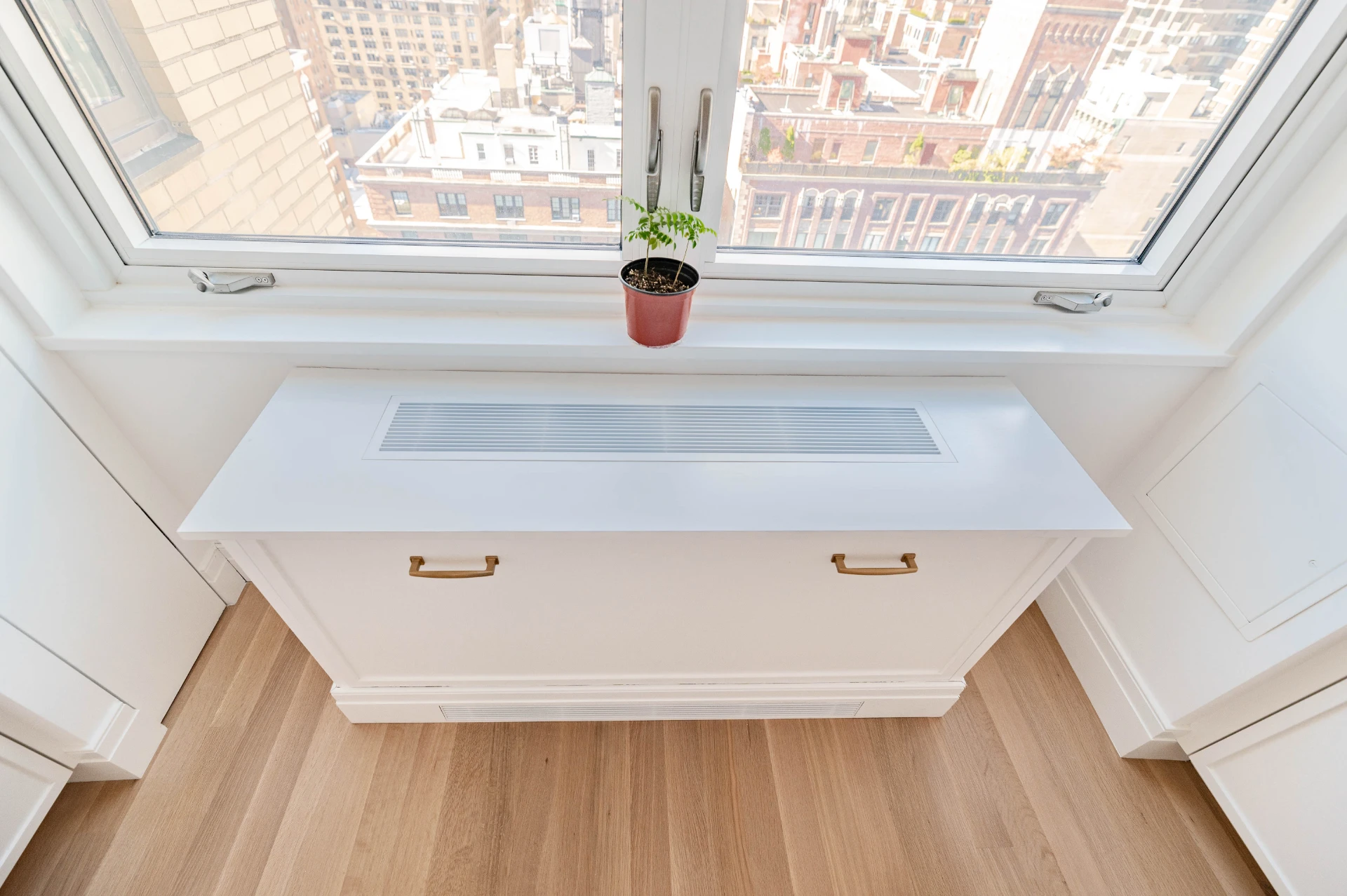 Custom window seat with brass pulls, city rooftops beyond the glass