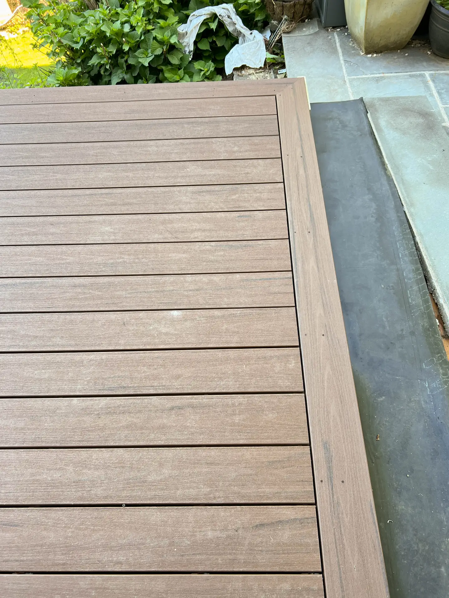 Composite deck boards meeting a bluestone patio