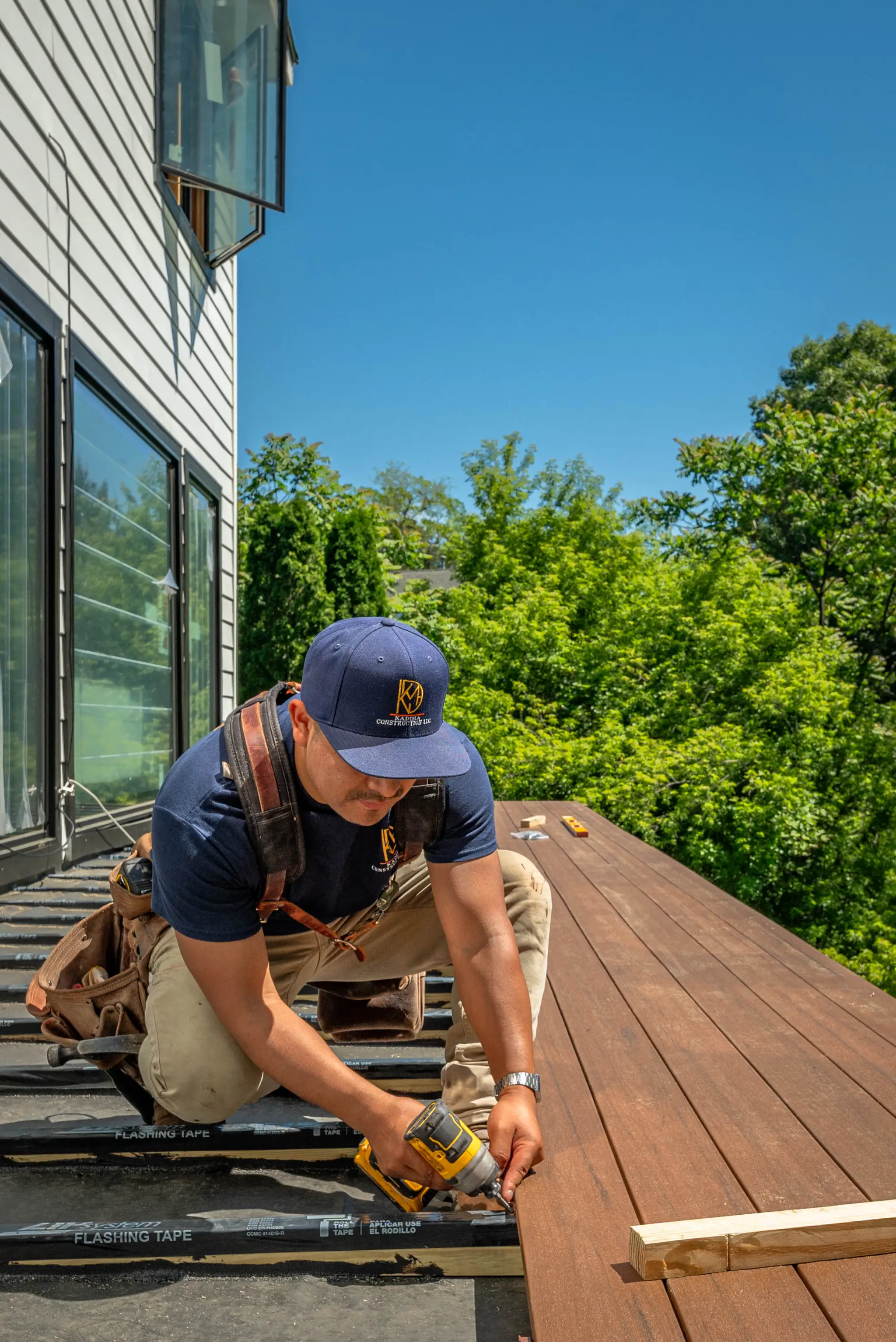 A Kadima Construction crew member driving a screw into a composite deck board
