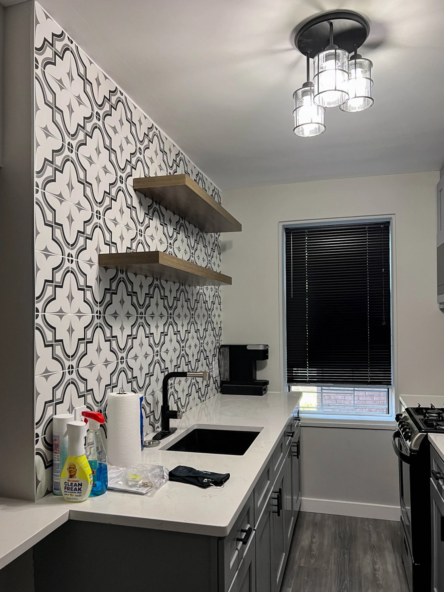 Floating wood shelves over patterned tile with a modern flush mount light