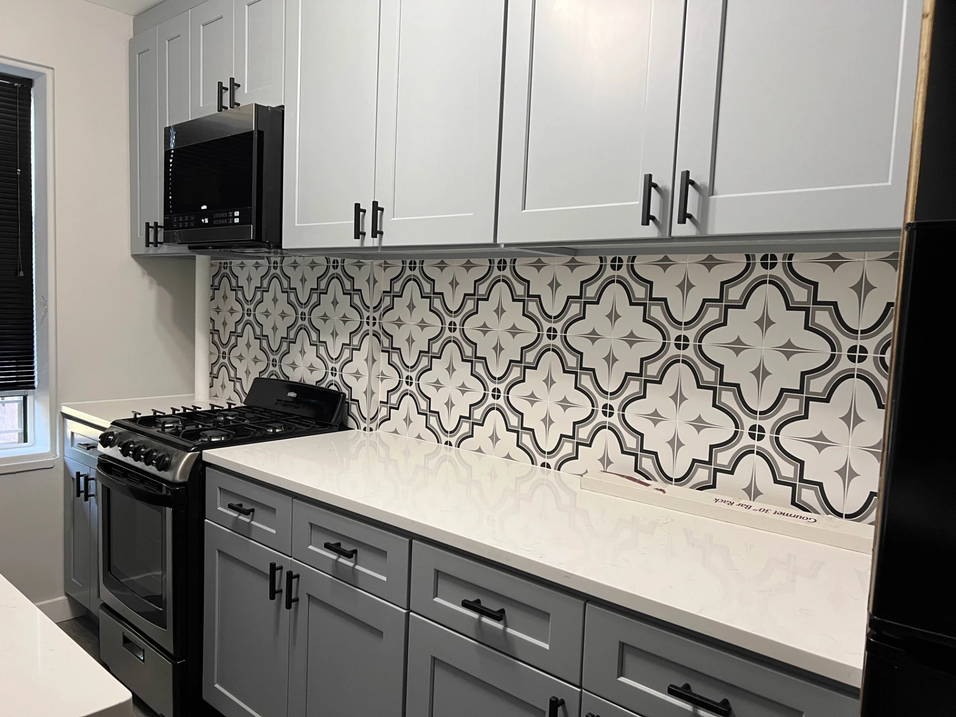 Finished kitchen with a gas range, white quartz counters and patterned tile