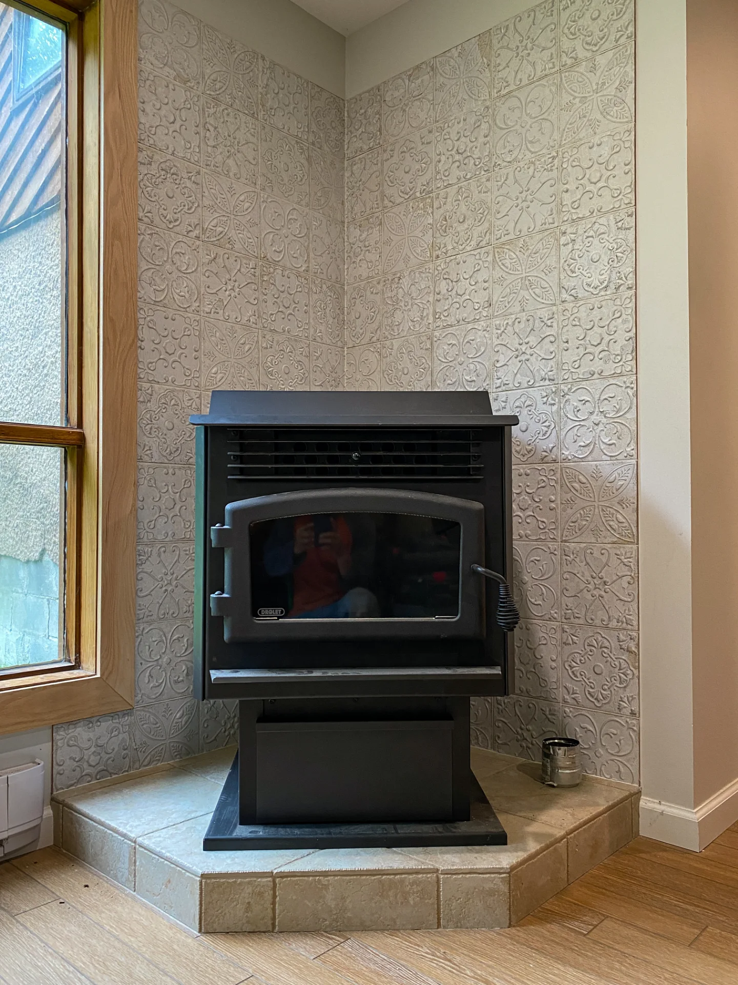 Textured white tile wall behind a stove, framed by a wood window surround