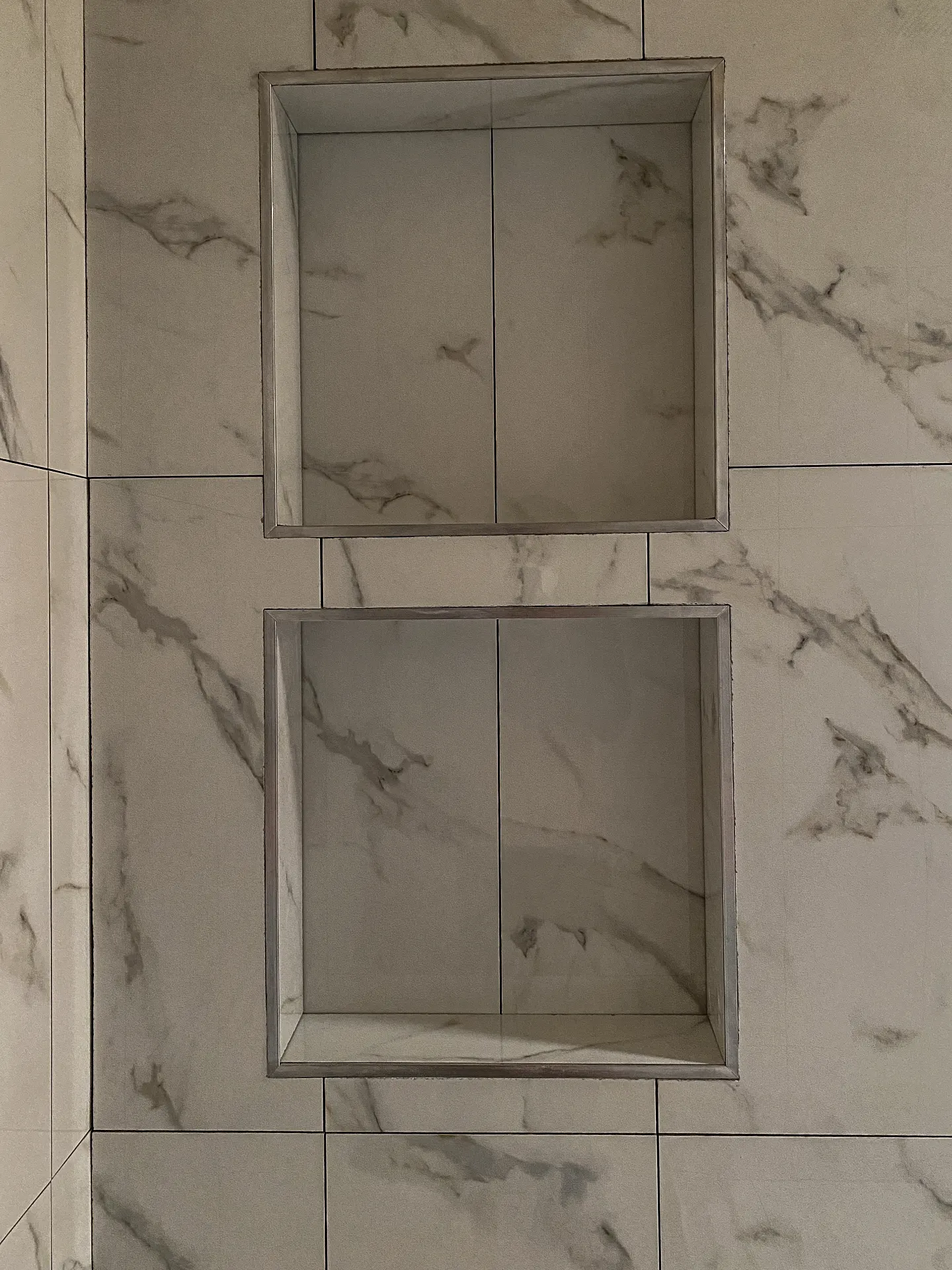Detail of a tiled shower niche in marble look tile